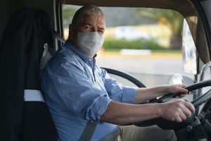 caminhoneiro com máscara de proteção no volante